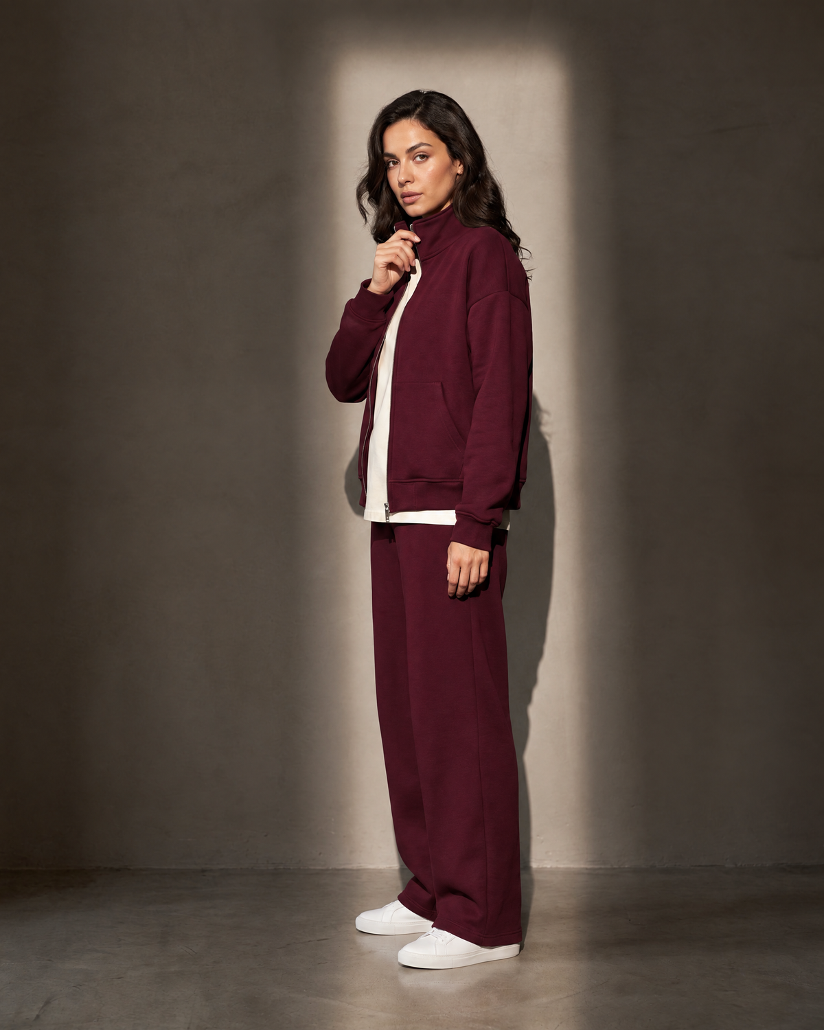 Elva Zip Set in burgundy, in profile against a warm greige wall