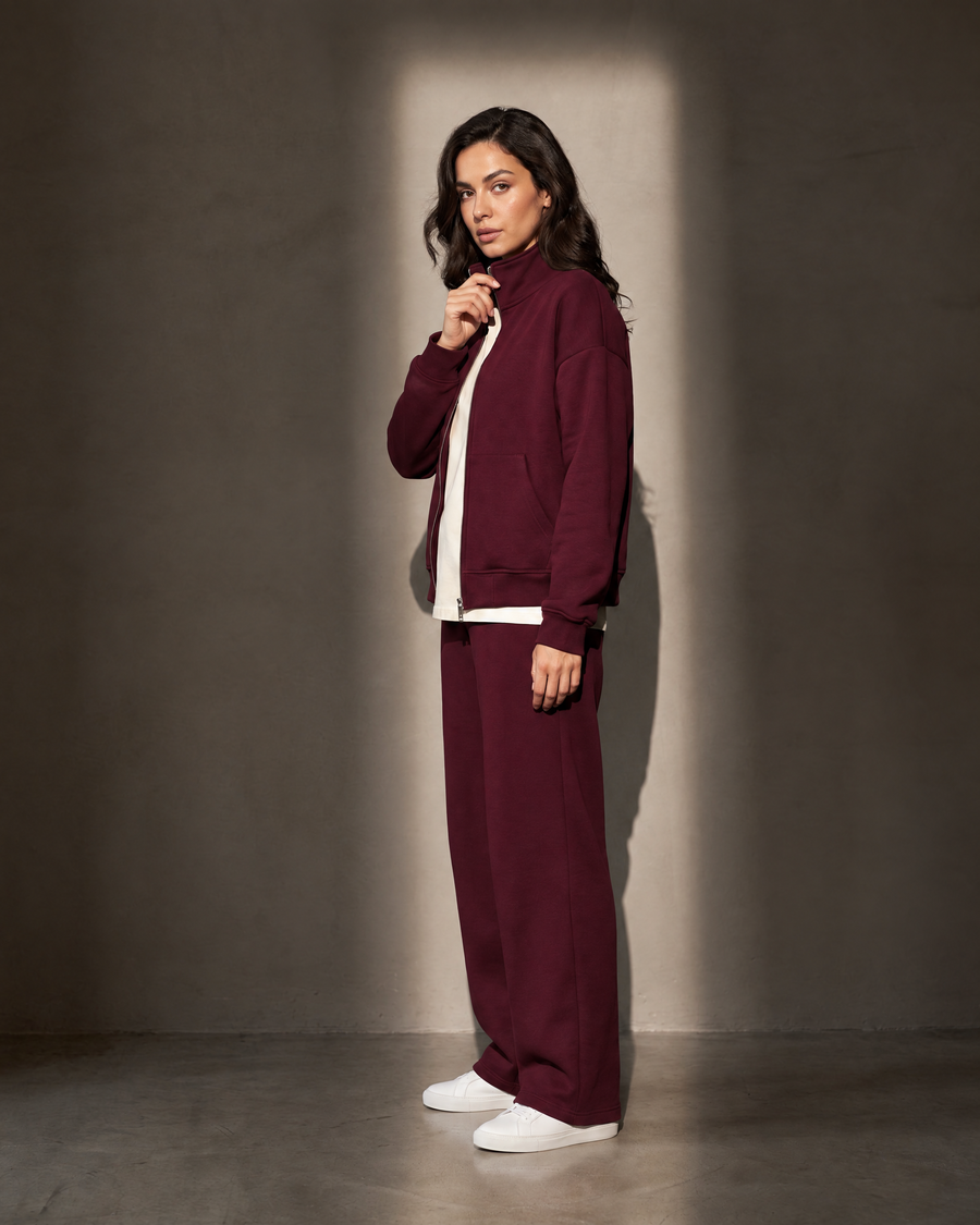 Elva Zip Set in burgundy, in profile against a warm greige wall