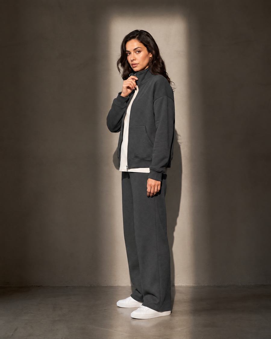 Elva Zip Set in charcoal, in profile against a warm greige wall
